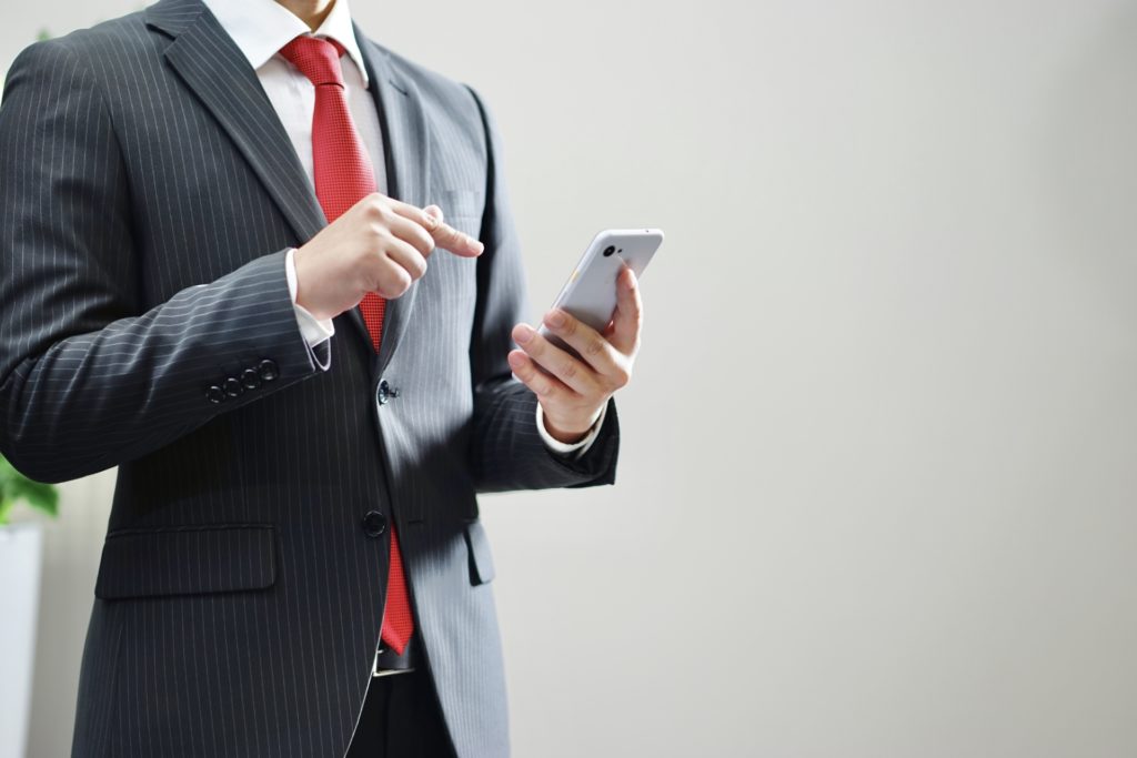 「スマートフォンを触るビジネスマン」の画像