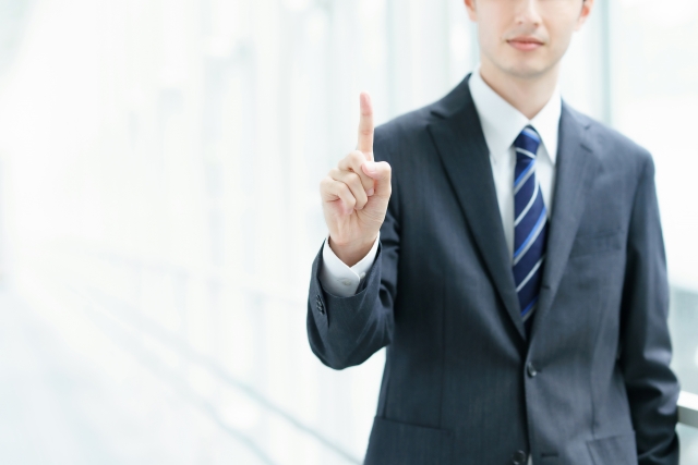 「右手人差し指を立てるビジネスマン」の画像