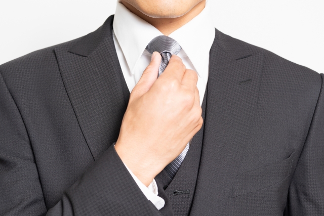 ネクタイを整えるスーツを着た男性の画像