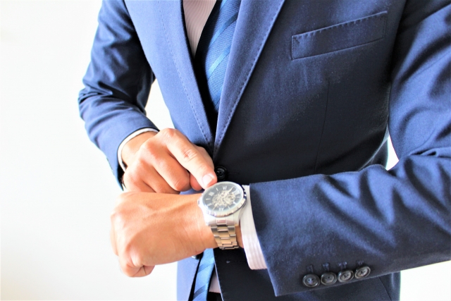「腕時計で時間を確認するスーツを着た男性」の画像