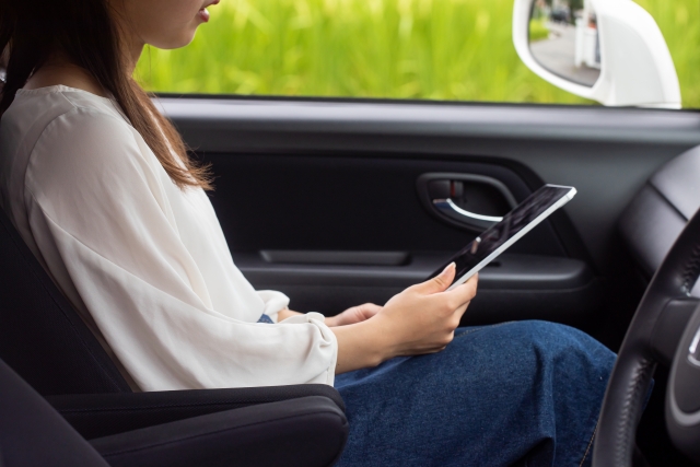 車の助手席で携帯を触る女性の画像